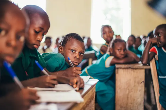Children writing in exercise books at their desks