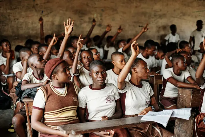 Pupils raising their hands in a crowded classroom